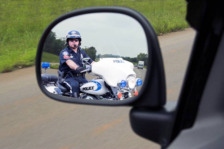 Police officer on motorcycle in rear mirror view